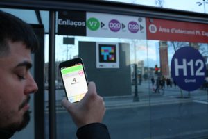 Imagen en la que se observa a Pedro Esquiva (@linconware ), miembro con discapacidad visual del equipo de I+D de Neosistec. Pedro se encuentra En una Parada de autobús de la Plaza Espanya de Barcelona, en la que se ha implantado la tecnología NaviLens.