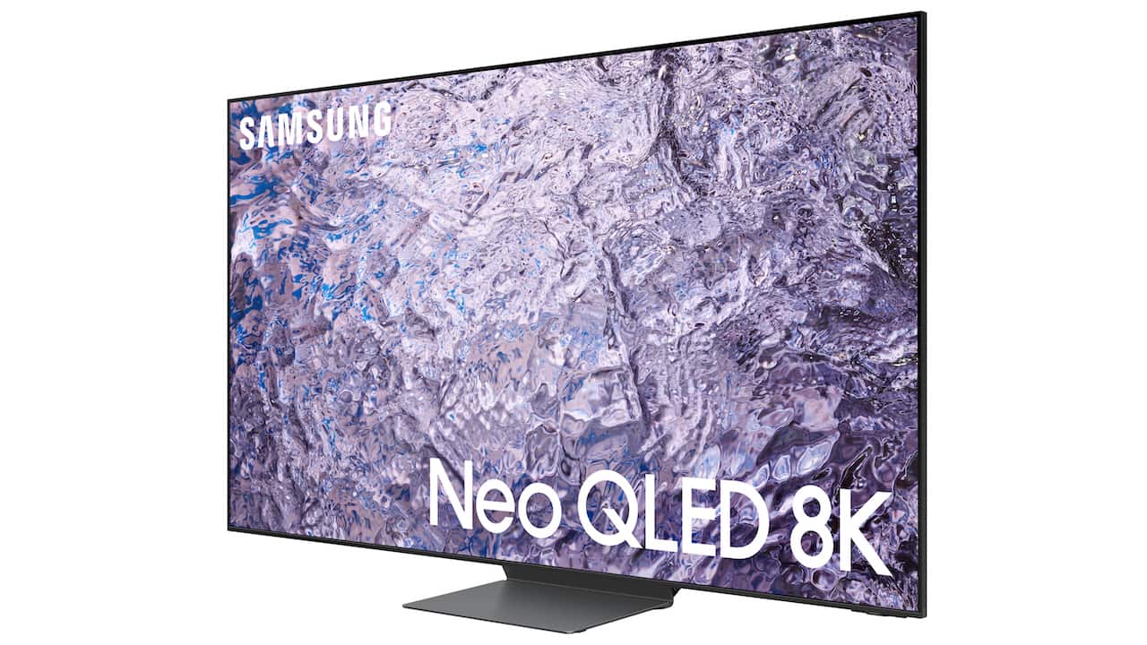 La imagen muestra un moderno televisor Samsung Neo QLED 8K. La pantalla del televisor muestra un gráfico abstracto con texturas que parecen aguas tumultuosas o una formación rocosa con tonos azules y grises, lo que podría ser una demostración de la alta definición y calidad de imagen que es capaz de producir. En la esquina superior izquierda de la pantalla, se encuentra el logo de Samsung. En la parte inferior de la pantalla, centrado, se puede ver el texto "Neo QLED 8K" en letras grandes y blancas, destacando el modelo y la resolución del televisor. El diseño del televisor es delgado y minimalista, con bordes muy finos, lo que sugiere una experiencia visual inmersiva. El aparato está montado sobre una base simple y elegante que parece robusta y diseñada para complementar el estilo delgado del televisor.