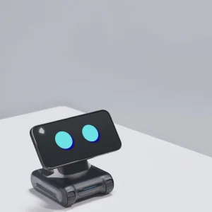 Imagen en la que se observa una única unidad negra sobre una superficie blanca limpia, con fondo completamente blanco. La composición es minimalista y centrada. El robot está ligeramente inclinado hacia la derecha, con la pantalla mostrando dos grandes círculos azul turquesa perfectamente simétricos que representan ojos abiertos. La base frontal incluye la franja luminosa azul en el centro y las orugas laterales bien definidas. La luz es suave y homogénea, sin distracciones, lo que enfatiza el diseño industrial del producto y su geometría compacta.